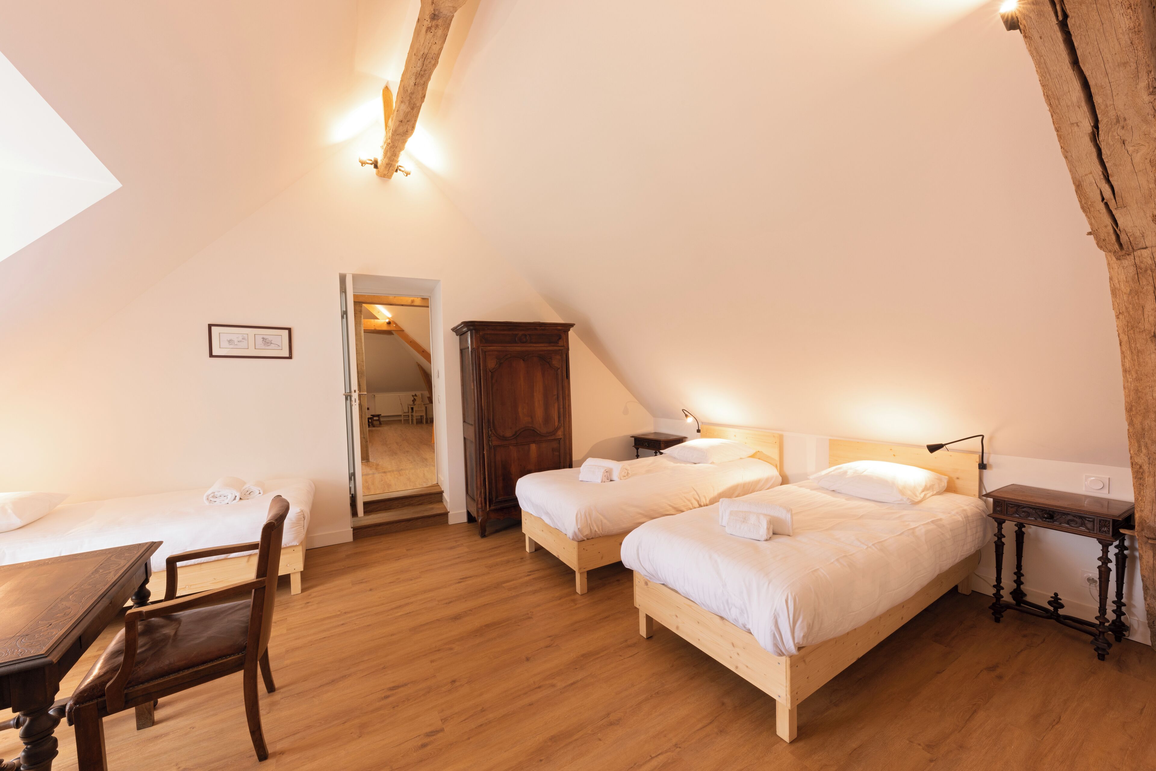 Una stanza accogliente e ben illuminata con due letti in legno, un tavolo di legno e una sedia.