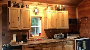 A cozy cabin-style kitchen with wooden cabinets, a refrigerator, a stove, and a microwave. - Beautiful Cabin in the woods  Allegany County NY (Belmont)
