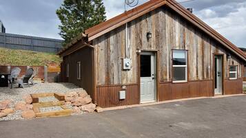 A rustic wooden building with a sloped roof, a front door, and a window.