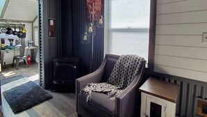 A cozy living room with a leather armchair, a small white cabinet, and a fireplace. - Pikes Peak Views: One Block to Downtown (Woodland Park)