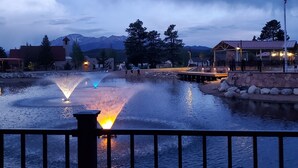 A calm water feature with fountains, surrounded by a stone wall and a flagpole. - Pikes Peak Views: One Block to Downtown (Woodland Park)