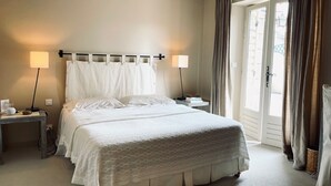 A neatly made bed with a white duvet, two bedside lamps, and a window with curtains. - Charm in Luberon (Ménerbes)