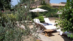 A garden with outdoor seating and a stone building in the background. - Charm in Luberon (Ménerbes)