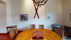 Un comedor con una mesa de madera, sillas y un tablero de ajedrez. Hay dos obras de arte enmarcadas en las paredes.