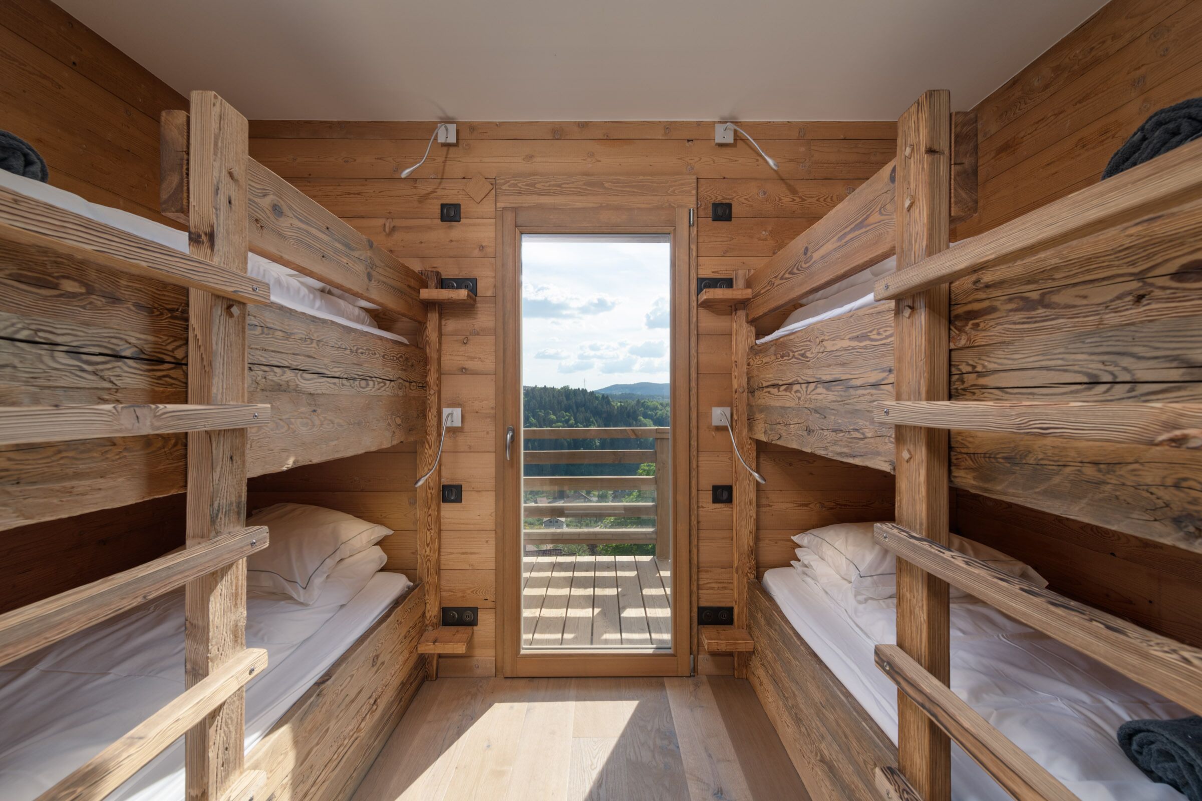 Una cabaña de madera con literas, una puerta de madera y vistas al exterior.