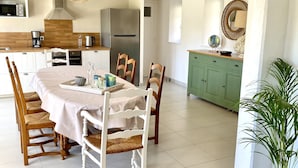 A modern kitchen with a central island, white cabinetry, and a dining area with a round table and chairs. - A traditional Breton vacation home near the sea (Roscoff)