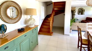 A spacious room with a wooden staircase, a teal cabinet, and a dining area with wooden chairs. - A traditional Breton vacation home near the sea (Roscoff)