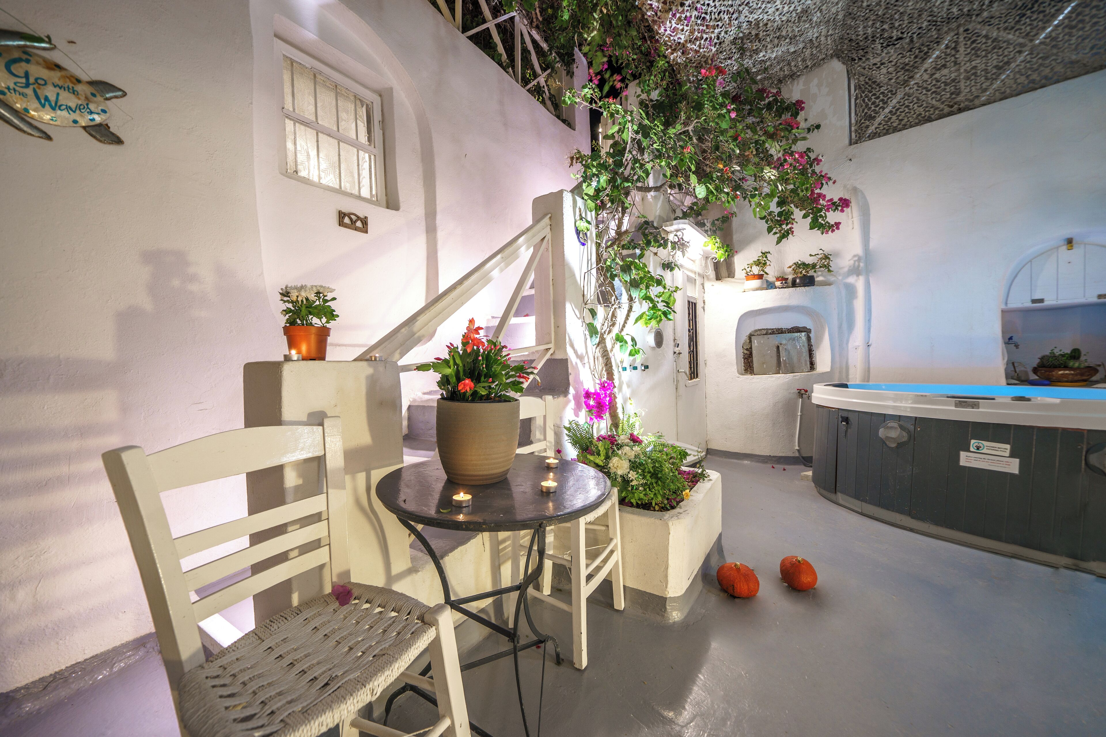 A cozy outdoor seating area with a wooden bench and table, surrounded by potted plants and flowers.
