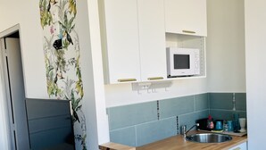 A compact kitchen with white cabinets, a microwave, a sink, and a dishwasher. - Waterfront studio, sea view 1st line beach (Palavas)