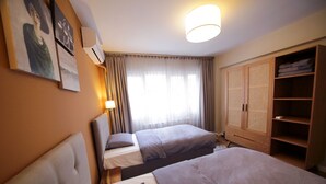 Ein Hotelzimmer mit zwei Betten, einem Schrank und einem Fenster mit Vorhängen.