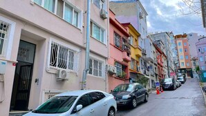 Eine schmale Straße, gesäumt von mehrstöckigen Gebäuden, von denen einige Balkone und Klimaanlagen haben.