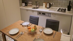 Eine moderne Küche mit weißen Schränken, einer Mikrowelle und einem Holzespeisesaal für vier Personen.