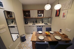 Une cuisine compacte avec un coin repas, équipée d’un four à micro-ondes, d’un évier et d’appareils électroménagers modernes.