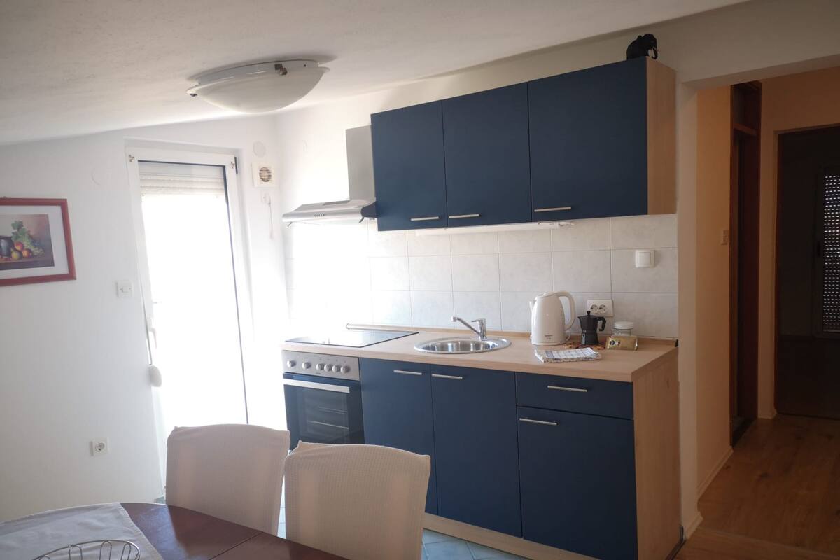 A compact kitchen with dark blue cabinets, a white countertop, and a small oven.
