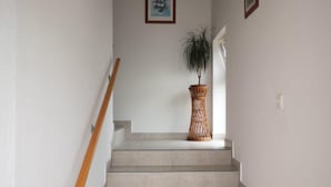A staircase with a wooden handrail, a woven basket on the landing, and two framed pictures on the walls. - Apartments Tara (Razanac)