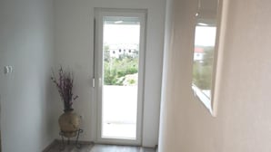 A hallway with a wooden floor, a door leading outside, and a potted plant. - Apartments Tara (Razanac)