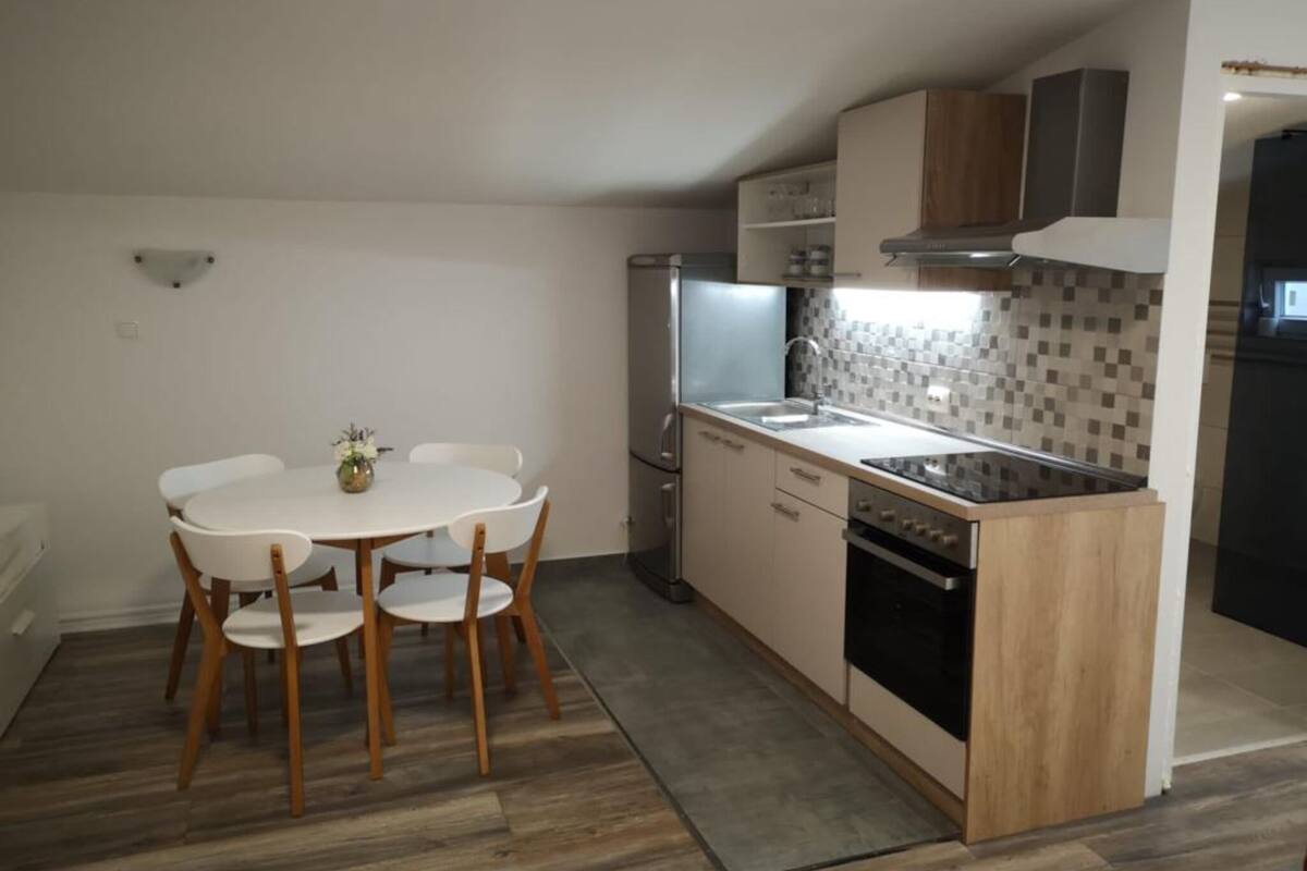 A compact kitchen with a dining table, chairs, a refrigerator, a stove, and a sink.