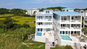 Un hôtel de plusieurs étages situé au bord de l’eau, doté de balcons, d’une piscine et offrant une vue sur la végétation et l’étendue d’eau environnantes.