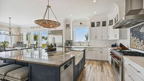 Une cuisine spacieuse dotée d’un grand îlot central, d’appareils électroménagers modernes et offrant une vue sur l’extérieur.