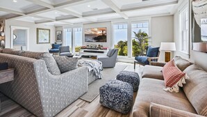 Un salon spacieux avec un plafond haut, de grandes fenêtres et une vue sur l’extérieur.