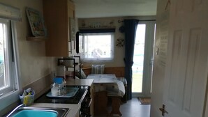 Eine kleine Küche mit Spüle, Herd und einem Fenster mit Vorhängen.