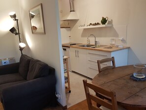 A compact living space with a kitchenette, a dining area, and a sofa.