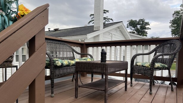A wooden deck with wicker furniture and a white railing.