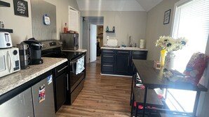 A modern kitchen with stainless steel appliances, wooden flooring, and a central island.