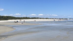 Ein Strand mit weitem, sandigem Ufer und sanft abfallendem Hang zum Wasser.