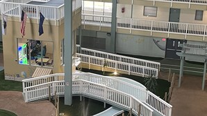 Ein mehrgeschossiges Atrium mit weißen Geländern, einer zentralen Wasserspiele und einem Spielbereich für Kinder.