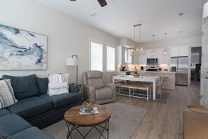 A modern living room with a sofa, a coffee table, and a dining area with a table and chairs.