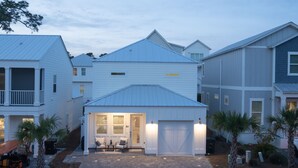Ein Wohngebäude mit Garage, überdachter Veranda mit Sitzgelegenheit und befestigter Auffahrt.