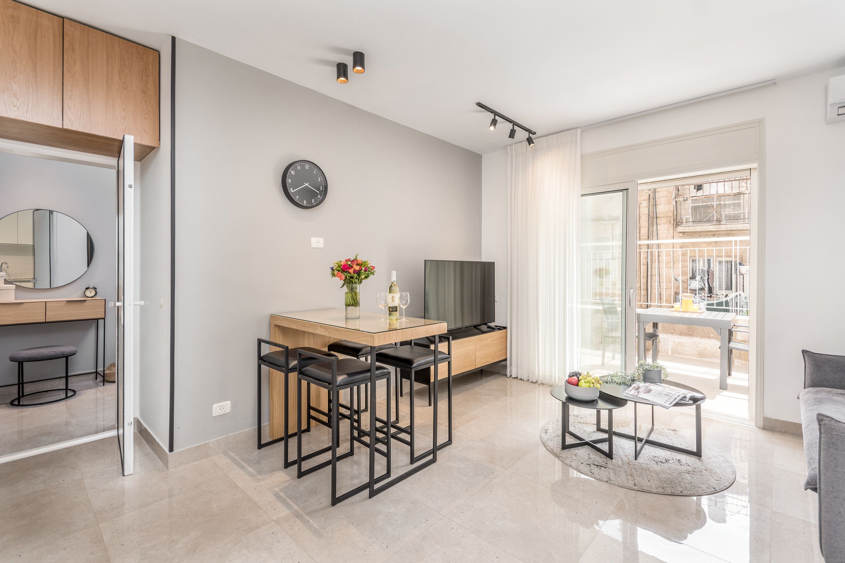 A modern kitchen with a dining area, a TV, and a large window.