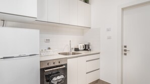 A modern kitchen with white cabinets, a stainless steel sink, a built-in oven, and a coffee maker. - Stylish one BDR with balcony (Jerusalem)