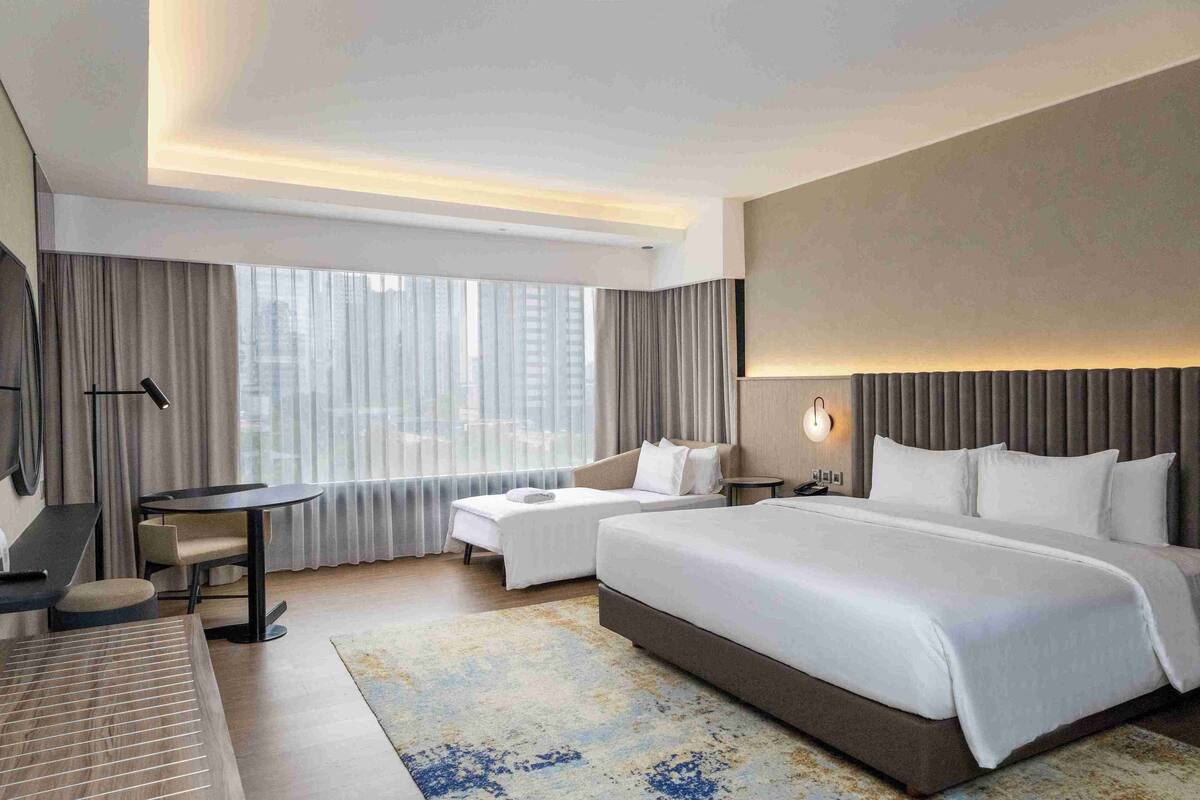 Een moderne hotelkamer met een groot bed, een bureau en een bank.