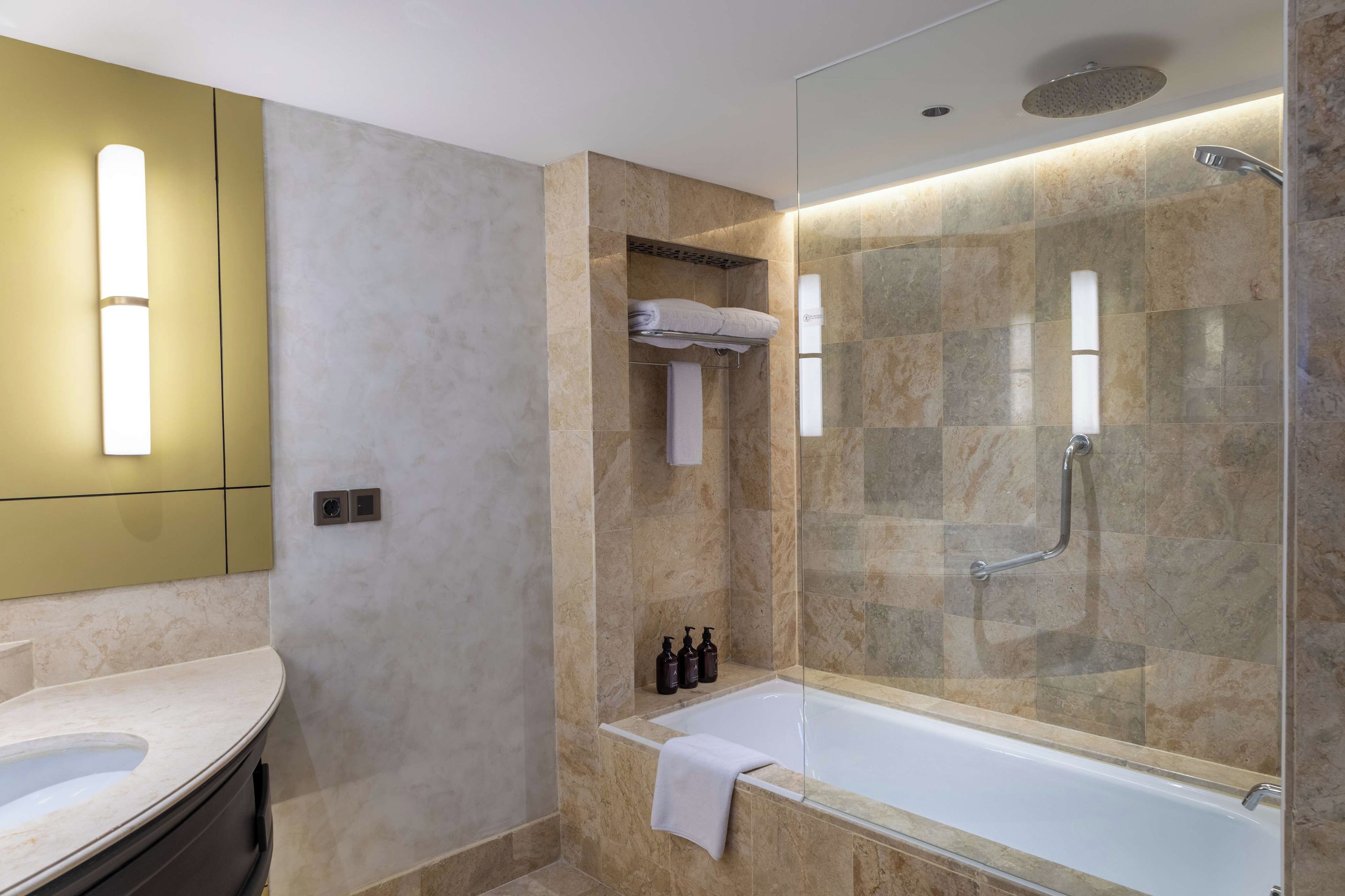 A modern bathroom with a glass-enclosed shower, a standalone bathtub, and a vanity with a mirror.