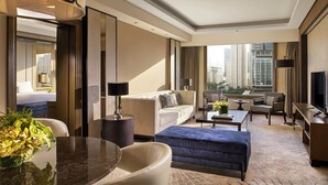 A modern hotel room with a large window offering a city view, a sofa, a coffee table, and a television. - Mangkuluhur ARTOTEL SUITES (Jakarta)