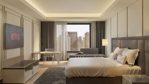 A modern hotel room with a large bed, a desk, a TV displaying 'NETFLIX', and a city view through the window. - Mangkuluhur ARTOTEL SUITES (Jakarta)