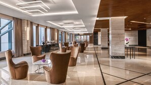 A spacious lobby with modern furniture, large windows, and a clean, polished floor. - Mangkuluhur ARTOTEL SUITES (Jakarta)