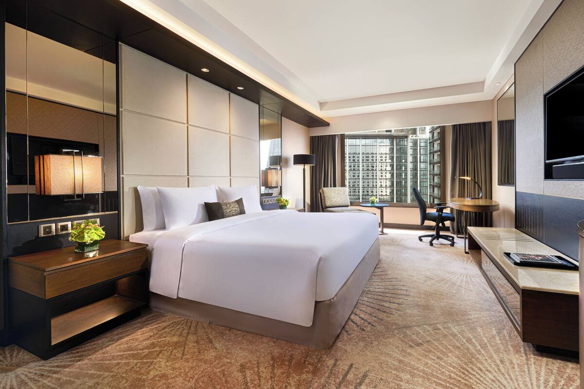 Een moderne hotelkamer met een groot bed, een bureau, een stoel en een televisie.
