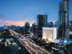 Un hôtel moderne doté d’une entrée imposante, situé au milieu d’immeubles de grande hauteur et bordé de rues très fréquentées.