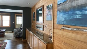 A room with wooden paneling, a kitchen counter, and a large painting of a lake.