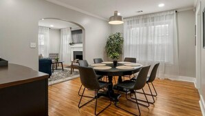 A dining area with a round table, black chairs, and a hanging light fixture. - The Enchanting Home @TU & Cherry Street (Tulsa)