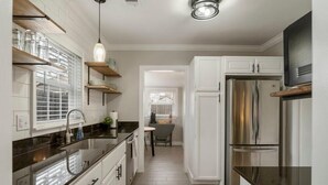 A modern kitchen with white cabinets, stainless steel appliances, and a black countertop. - The Enchanting Home @TU & Cherry Street (Tulsa)