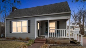 A single-story house with a gray exterior, a front porch with a white railing, and a number 1343 on the right side. - The Enchanting Home @TU & Cherry Street (Tulsa)
