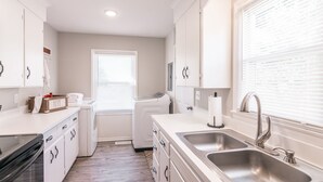 A modern kitchen with white cabinetry, a double sink, and a built-in oven. - Cozy House in Gallatin City Limits (Gallatin)