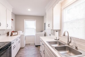 A modern kitchen with white cabinetry, a double sink, and a built-in oven.