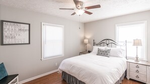 A bedroom with a bed, two bedside tables, a ceiling fan, and a motivational quote on the wall. - Cozy House in Gallatin City Limits (Gallatin)