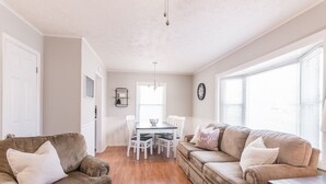 A spacious living area with two sofas, a dining table with chairs, and a large window providing natural light. - Cozy House in Gallatin City Limits (Gallatin)