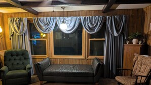 Una sala acogedora con un sofá de cuero, dos sillones y un aparador de madera.